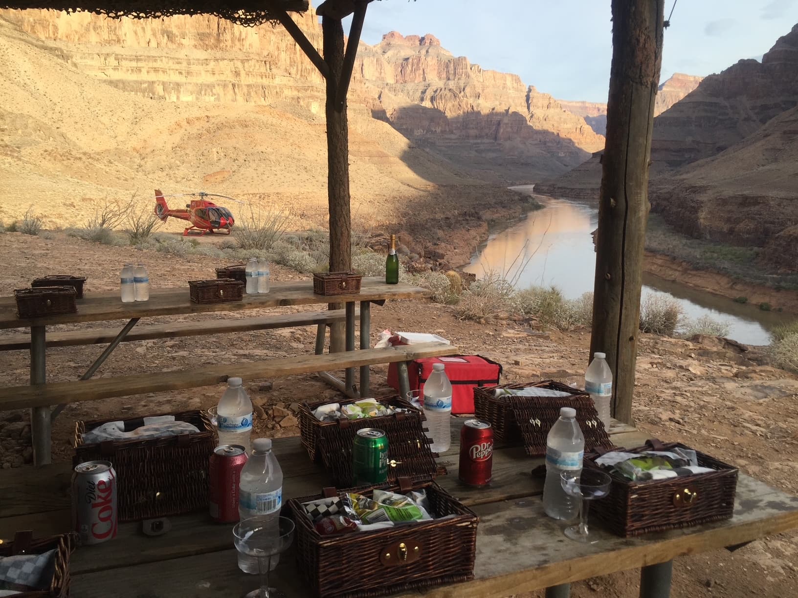 Papillon canyon-floor landing platform at the Grand Canyon West Rim: champagne bottle, wicker picnic baskets and the Colorado River on Hualapai land